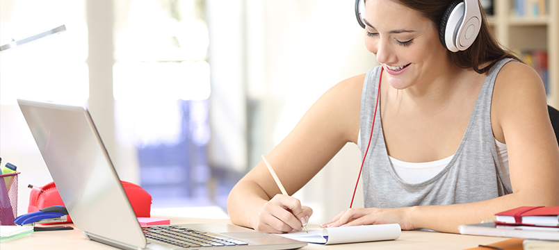 Girl taking notes with a laptop in front of her