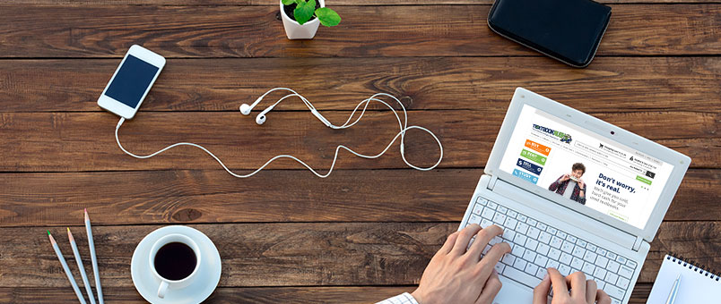 Overhead view of a desk with a laptop, headphones, coffee, and pencils