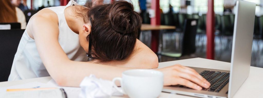 A woman laying with her head in a book while studying