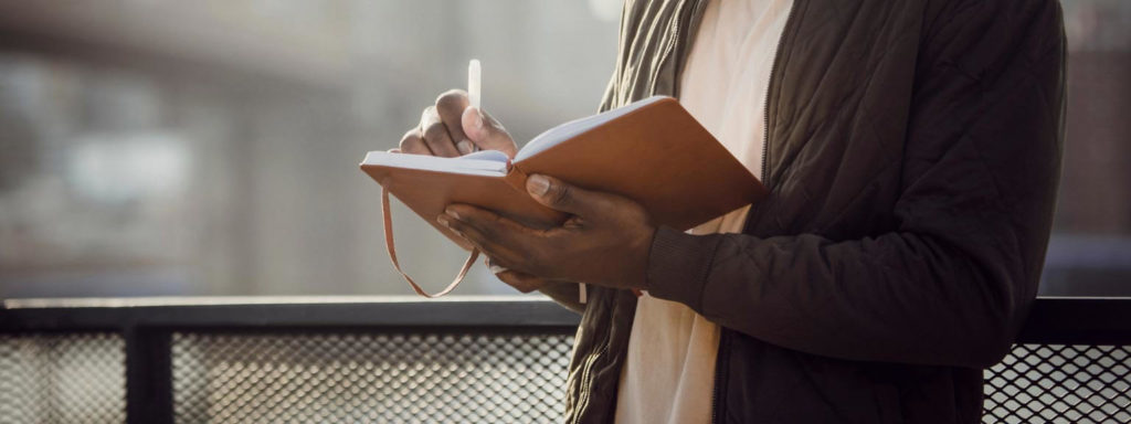 A man holding a notebook and writing in it